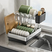 Modern black stainless steel 2 tier dish drainer rack holding green and white plates glassware and utensils