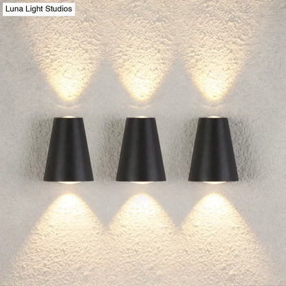 Modern black trapezoid wall light with three sleek conical sconces emitting warm light and maximum bulb wattage