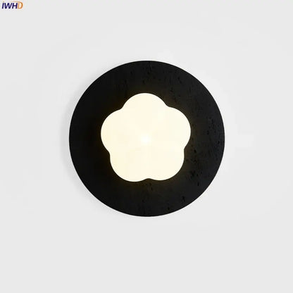 Modern black travertine wall lights with textured circular sconce and glowing four-petal flower led center by decorbites