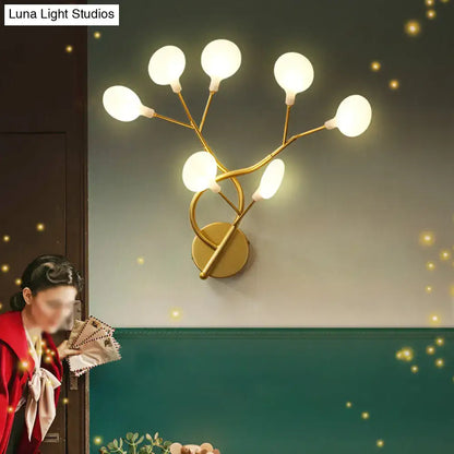 Gold-toned wall light with six frosted glass globes in a modern tree branch design 24 inch fixture for bedroom use