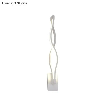 White led wall sconce with a sleek twisted design emitting warm white light for modern stairway or bedroom use