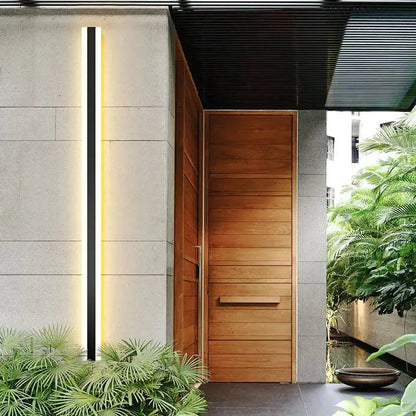 Modern black vertical led wall sconce ip65 waterproof next to a modern wooden door with horizontal slats and minimalist design