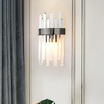 Modern black wall lamp with sleek metal ring and icicle crystal rods emitting warm light for dining room use