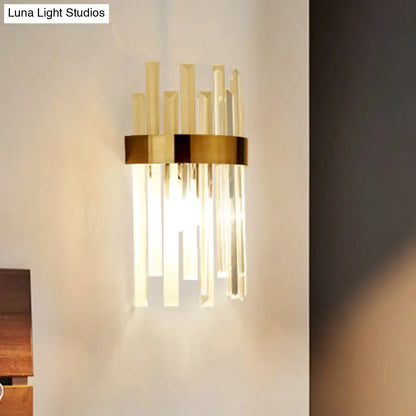 Modern black wall lamp with gold-toned metal base and vertical clear glass rods for dining room lighting
