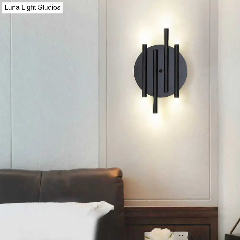 Modern black wall light with round backplate featuring vertical cylindrical rods and bulb bases for bedroom use