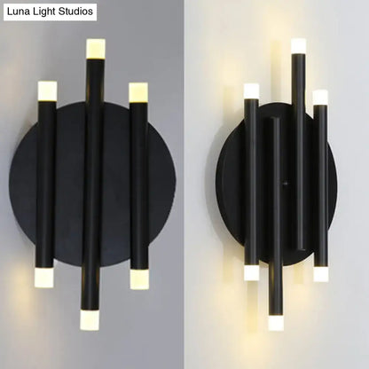 Modern black wall light with round backplate featuring three vertical cylindrical arms and frosted white led light caps