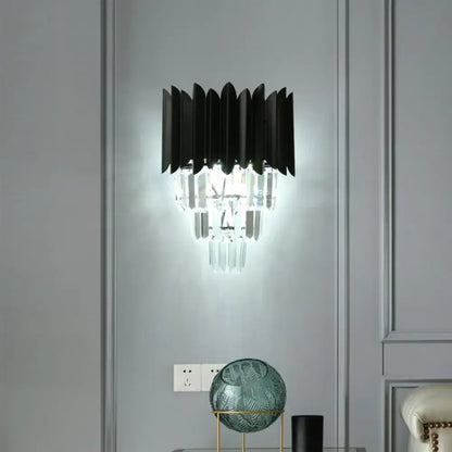 Modern black wall sconce with clear crystal prisms and layered fan-like shades for elegant bedroom lighting