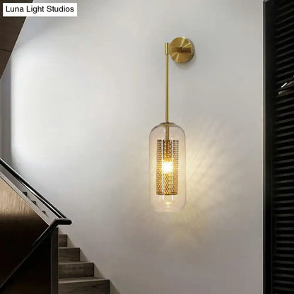Modern black wall sconce with clear glass cylindrical shade and intricate gold-toned perforated wire mesh interior
