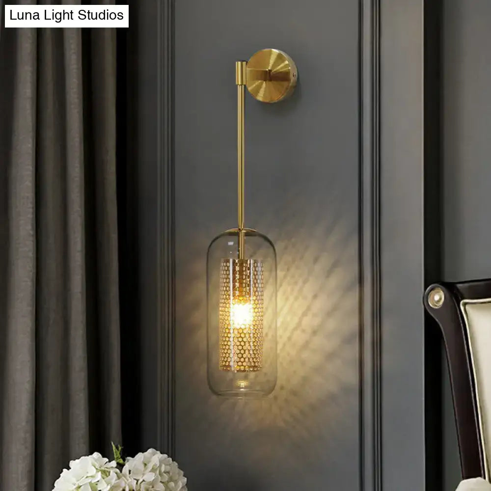 Modern black wall sconce with clear glass cylindrical shade and gold-toned wire mesh honeycomb pattern interior