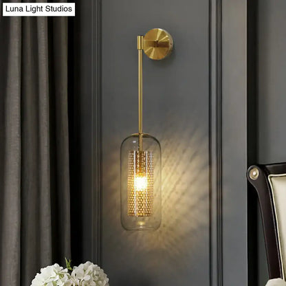 Modern black wall sconce with clear glass cylindrical shade and gold-toned wire mesh honeycomb pattern interior