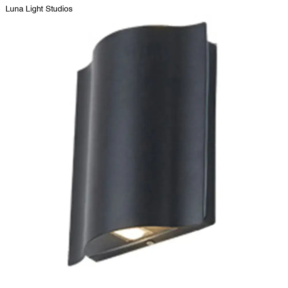 Modern black curved wall light with wavy metal shade and warm white light designed for patio use