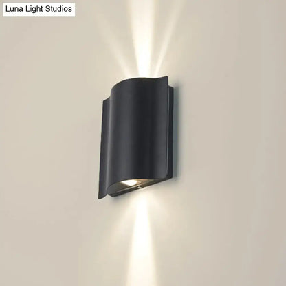Modern black curved wall light with wavy metal shade emitting warm white light for patio use