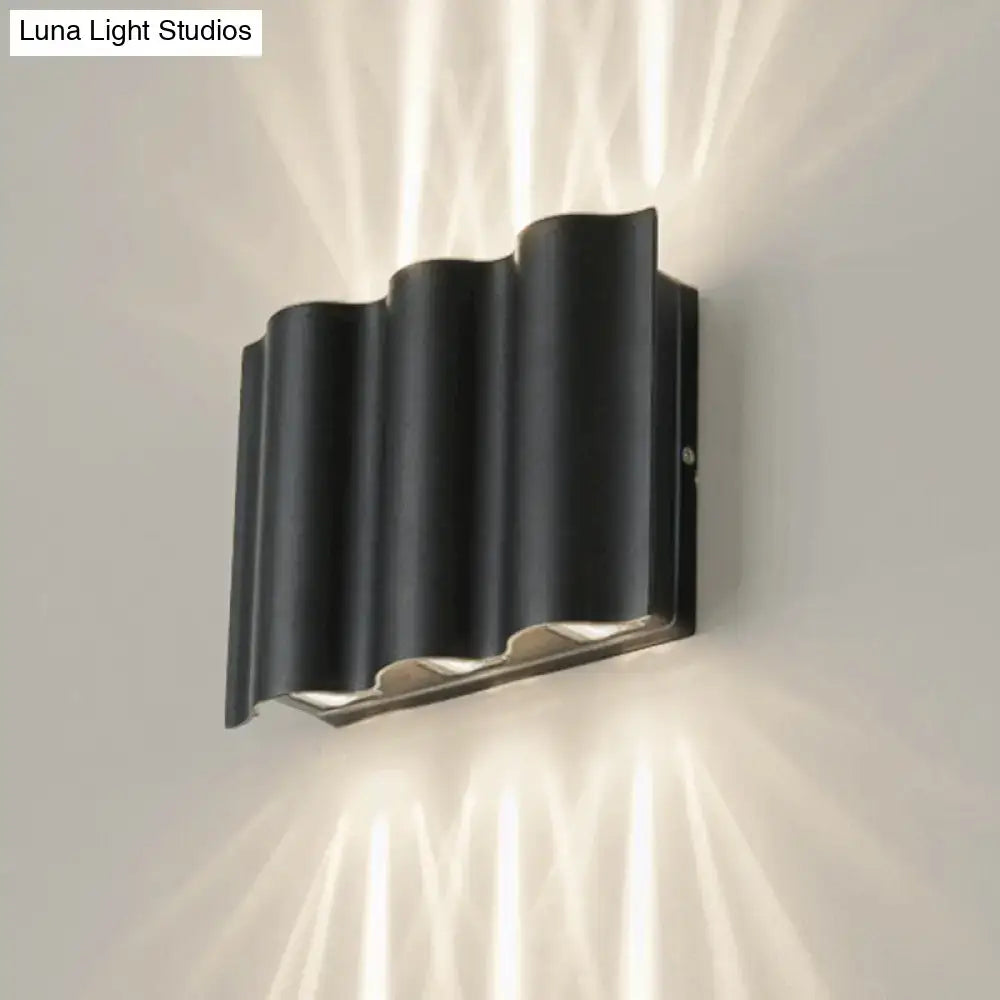 Modern black wavy metal shade wall light with sleek design and metallic accents emitting warm white light for patio use