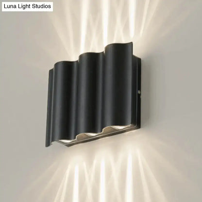 Modern black wavy metal shade wall light with sleek design and metallic accents emitting warm white light for patio use