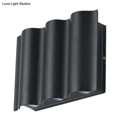 Black wavy metal shade wall light with sleek modern design emitting warm white light for patio use