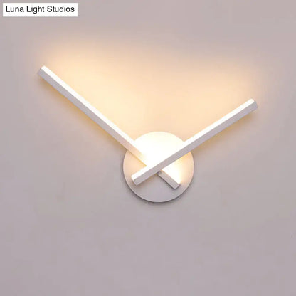 Modern black and white acrylic cross wall sconce with intersecting arms emitting warm white ambient light for bedroom use