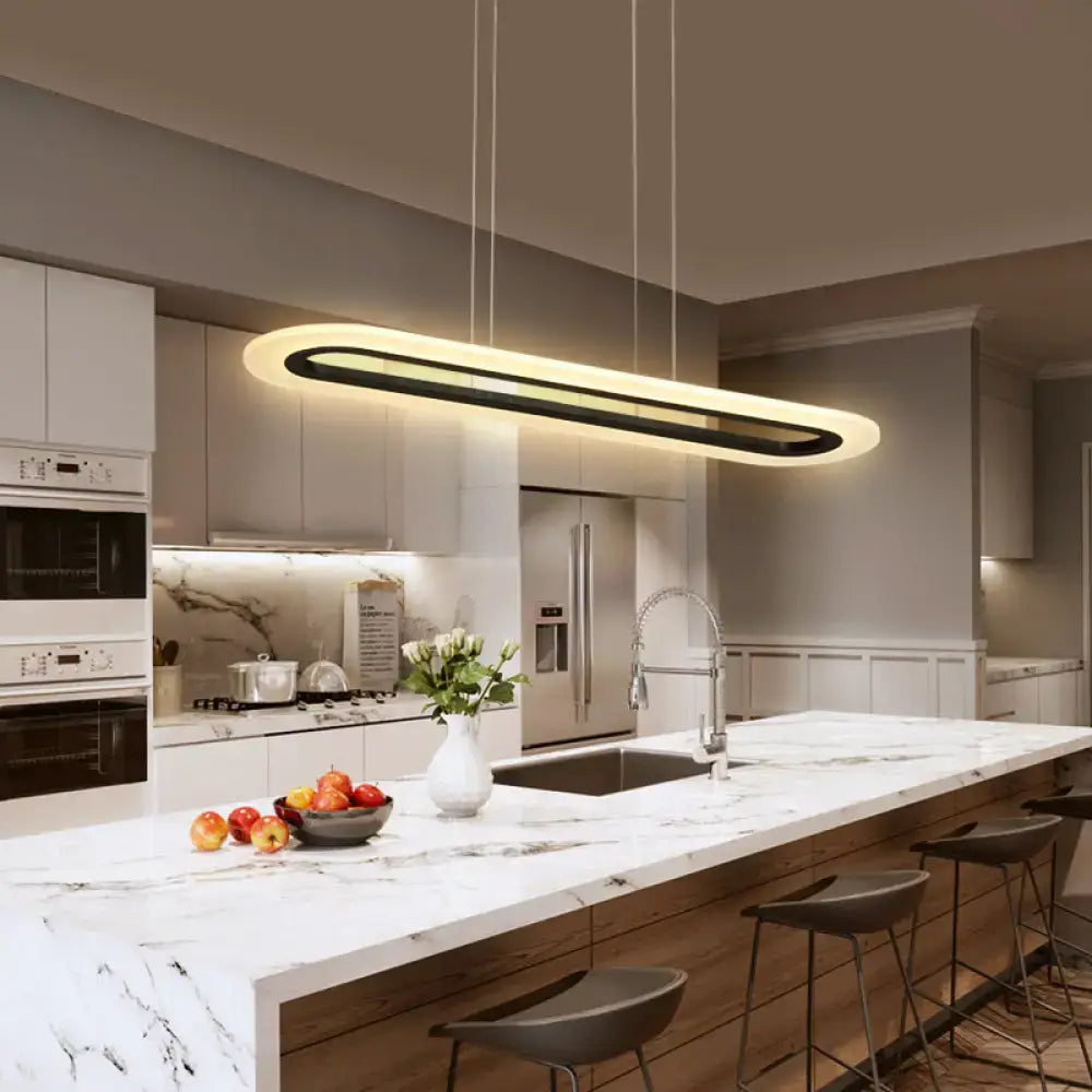 Modern oval acrylic oblong light fixture with sleek black and warm white design, remote control, above kitchen island