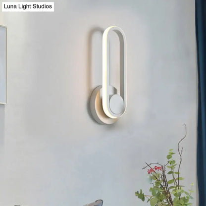 Modern black and white aluminum frame wall lamp with sleek oval design and layered accents emitting warm white light