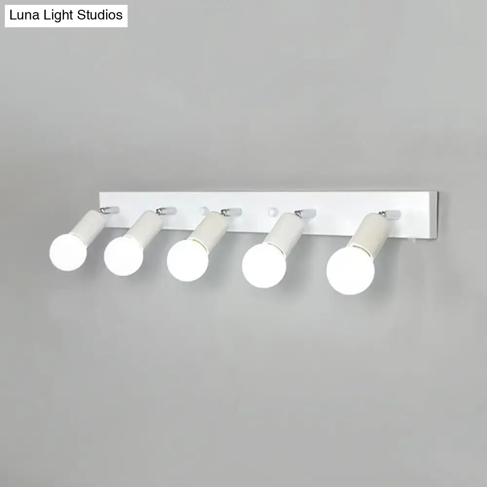 Modern black and white bedroom vanity light fixture with five exposed frosted glass cylindrical bulbs mounted on white wall