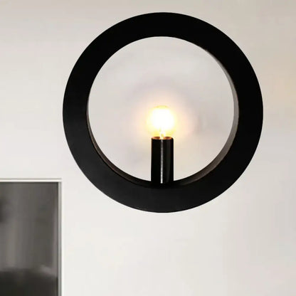 Modern black and white circle wall light featuring a black circular wall lamp with a central illuminated bulb for bedrooms