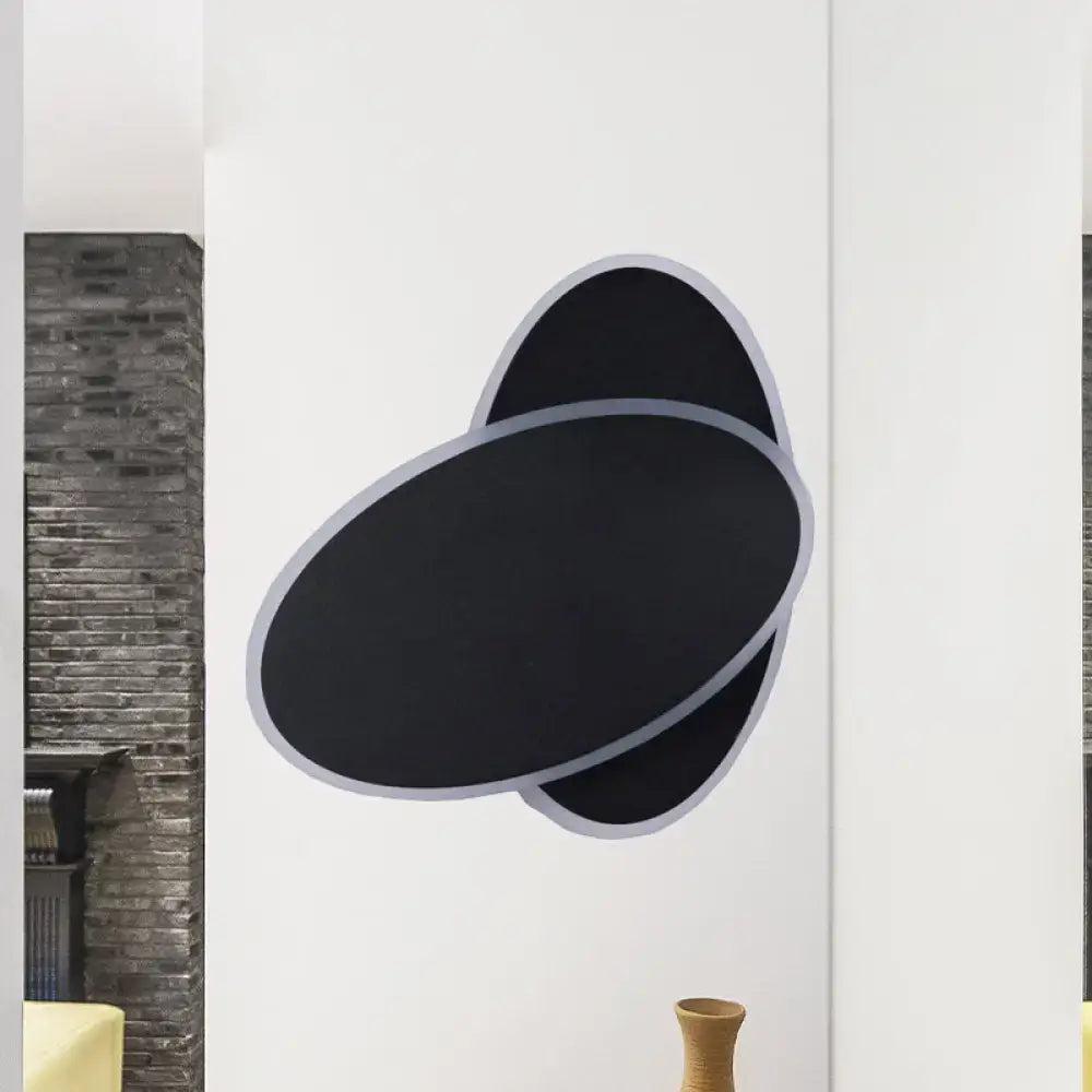 Modern black and white double oval wall sconce lamp with sleek silver outlined overlapping ovals for bedside lighting