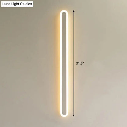 A sleek modern black and white elliptical acrylic flush wall sconce emitting warm white light for aisle lighting