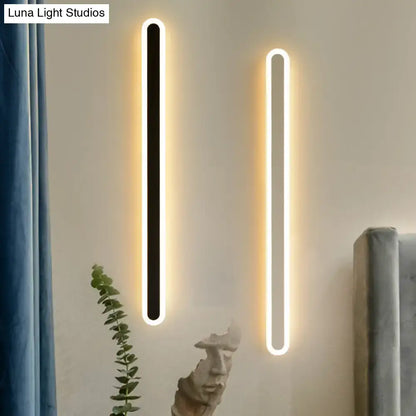 Two modern black and white elliptical acrylic wall sconces emit warm white light with minimalist rectangular frames