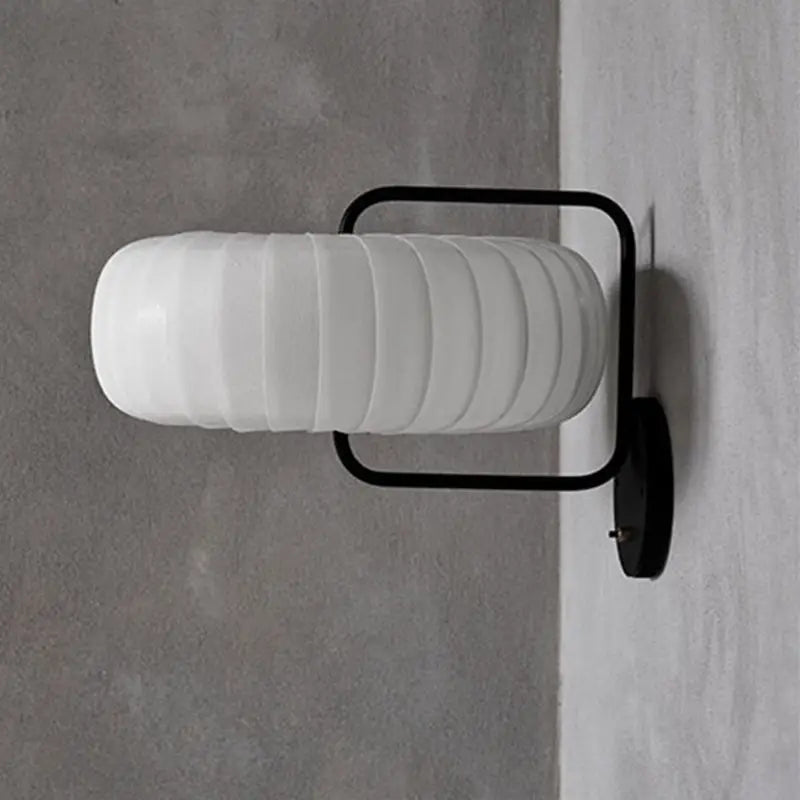 Modern black and white gathered fabric pumpkin wall sconce with white ribbed glass lamp and sleek black metal frame