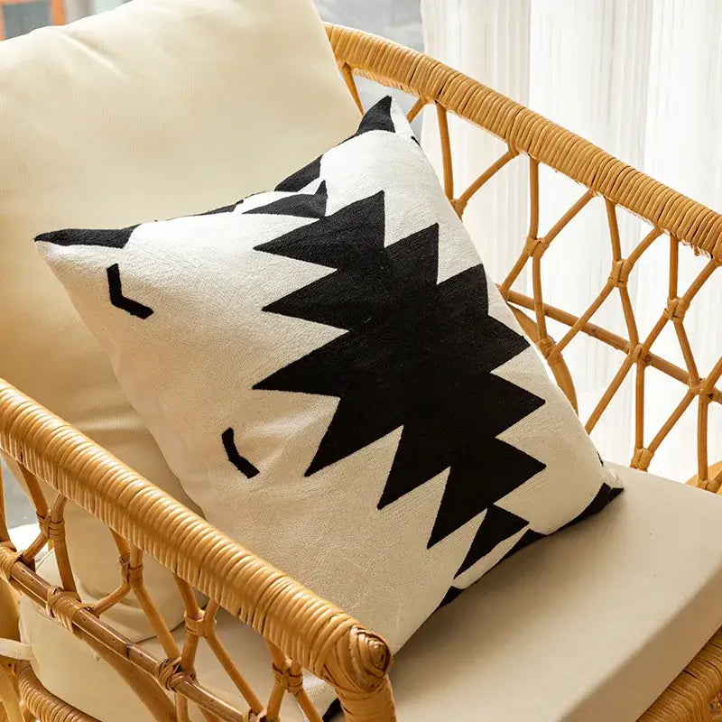 Cream-colored cushion cover with bold black geometric embroidered starburst pattern and soft stitched fabric texture