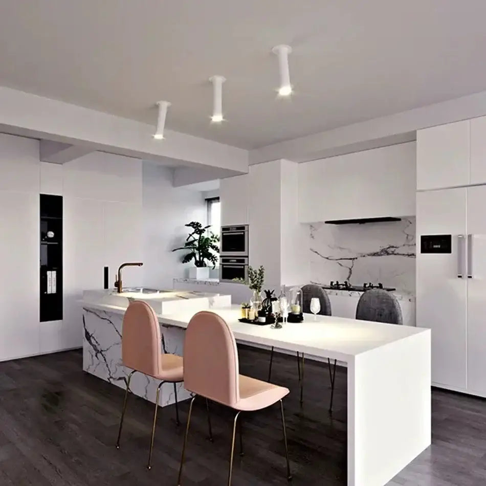 Modern black and white led bar ceiling spotlight illuminating a white marble kitchen island with integrated sink