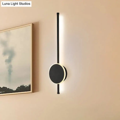 Modern black and white led wall sconce with sleek vertical rod and circular base featuring warm color temperature lighting