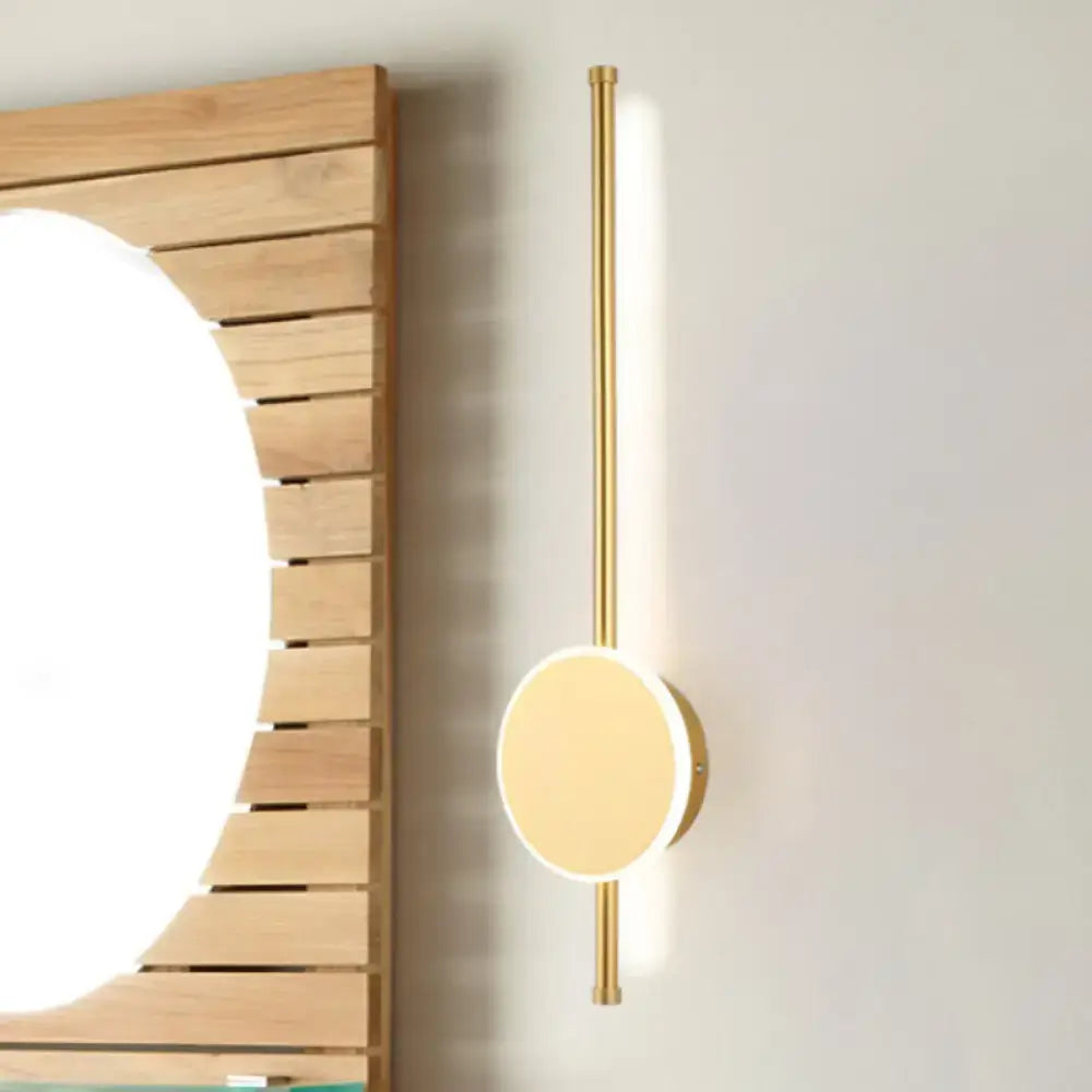 Gold-toned minimalist wall sconce with circular glowing light and warm color temperature for modern bedroom use