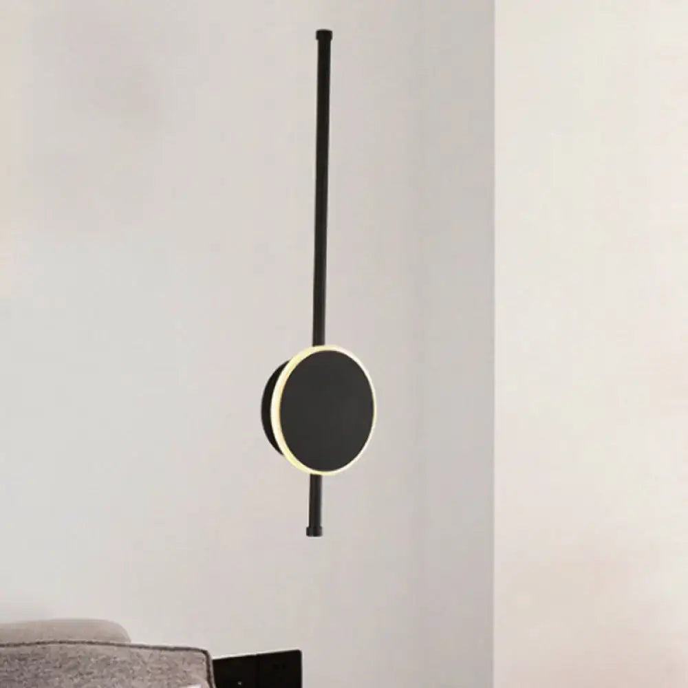 Black minimalist pendant light with circular illuminated face and sleek rod featuring warm color temperature for bedroom use