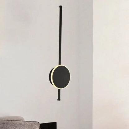 Black minimalist pendant light with circular illuminated face and sleek rod featuring warm color temperature for bedroom use