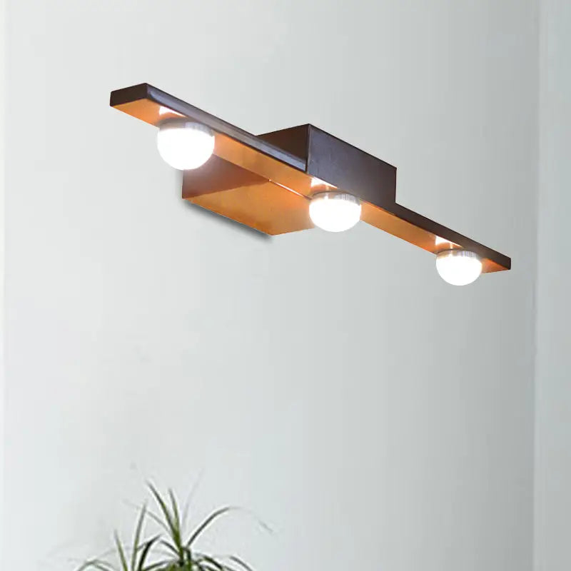 Modern black and white linear wall lighting with bronze finish and three spherical bulbs emitting warm white light