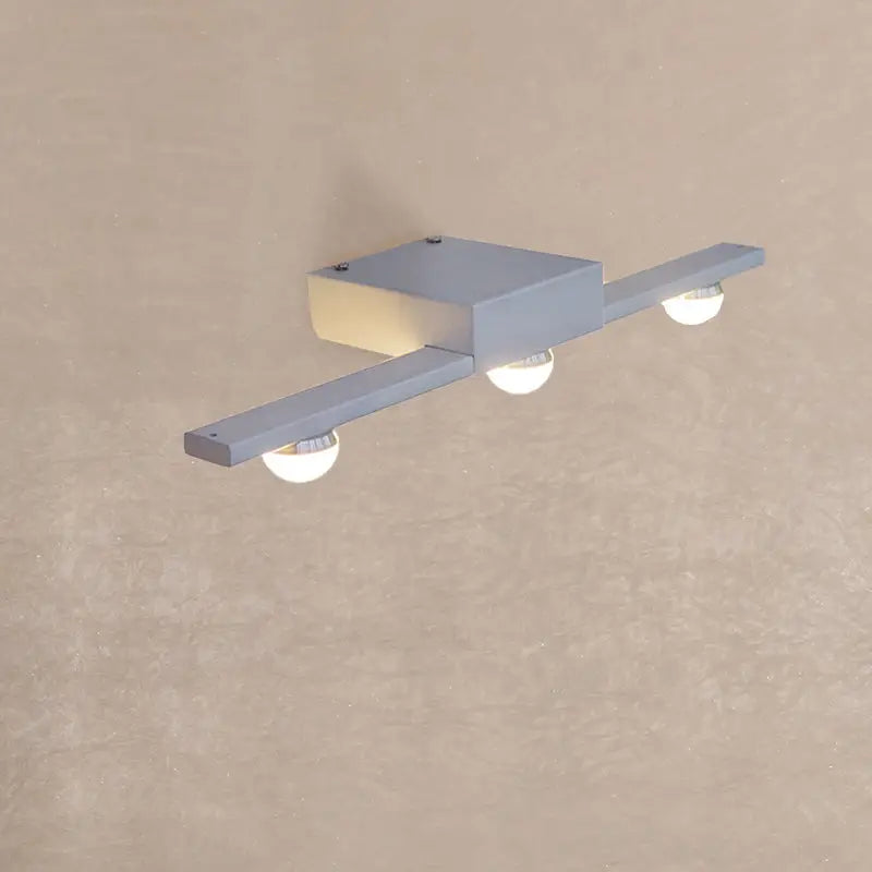 Modern black and white linear wall lighting with silver metallic fixture and three warm white spherical bulbs for bathroom vanity