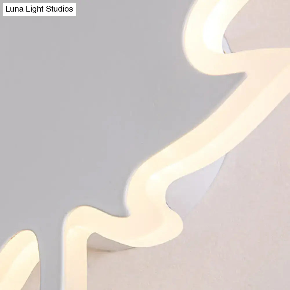 A modern black and white maple leaf sconce light with a softly glowing wavy led design and smooth plastic casing