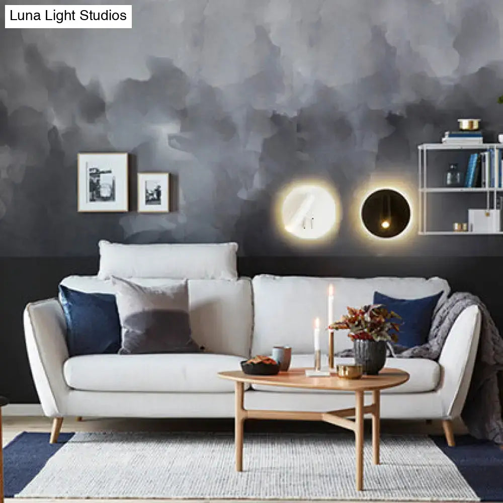 Modern black white metal acrylic wall lamp mounted above white sofa with navy and gray throw pillows in living room