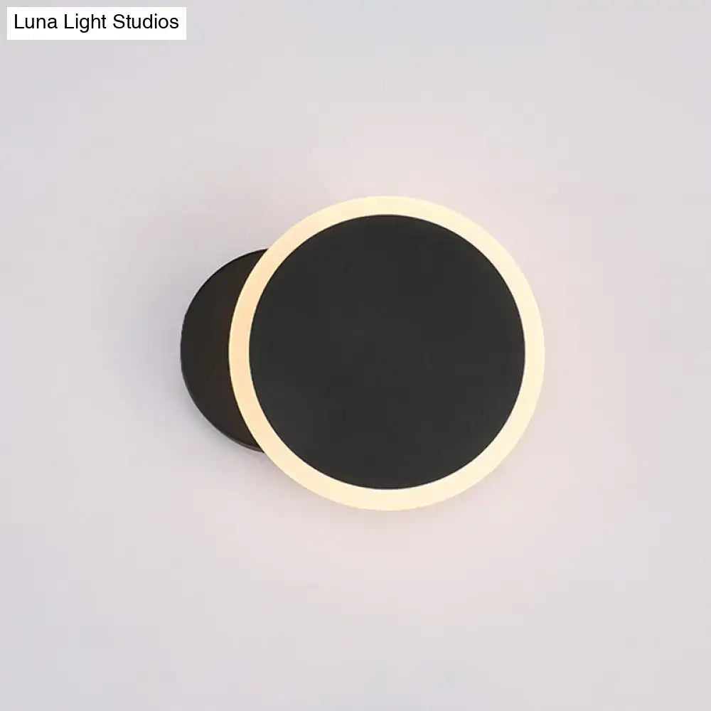 Modern black and white minimalist led wall sconce with a sleek black matte center and warm cream illuminated ring