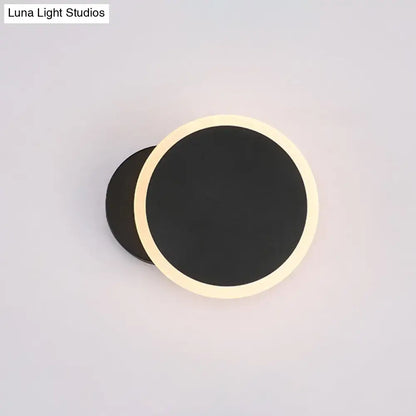 Modern black and white minimalist led wall sconce with a sleek black matte center and warm cream illuminated ring