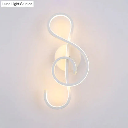 A sleek white wall lamp shaped like a musical note with an acrylic shade emitting a warm glow