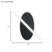 Modern black and white oval led sconce with diagonal light bar and warm white glow for stairway lighting