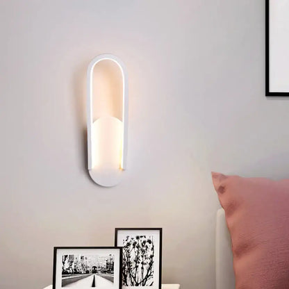 Modern black and white oval led wall sconce with warm white ambient lighting and sleek elongated oval design