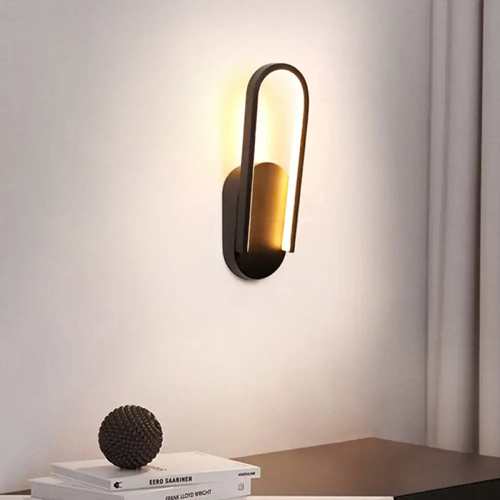 Modern black and gold wall sconce with sleek curved design featuring warm white color temperature light
