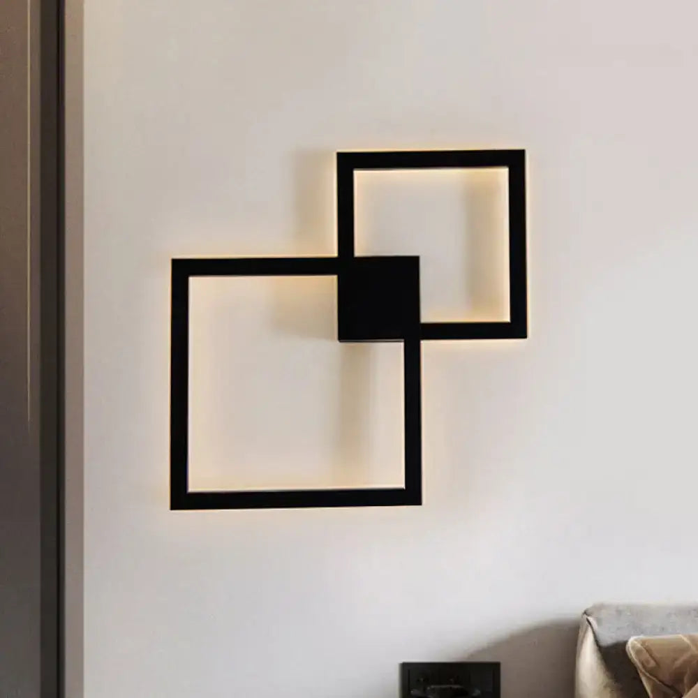 Modern black wall sconce with overlapping acrylic shade design providing warm ambient lighting for dining room