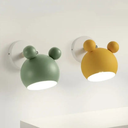 Two whimsical matte sage green and mustard yellow led wall lamps with rounded heads and spherical ears for bathroom mirrors