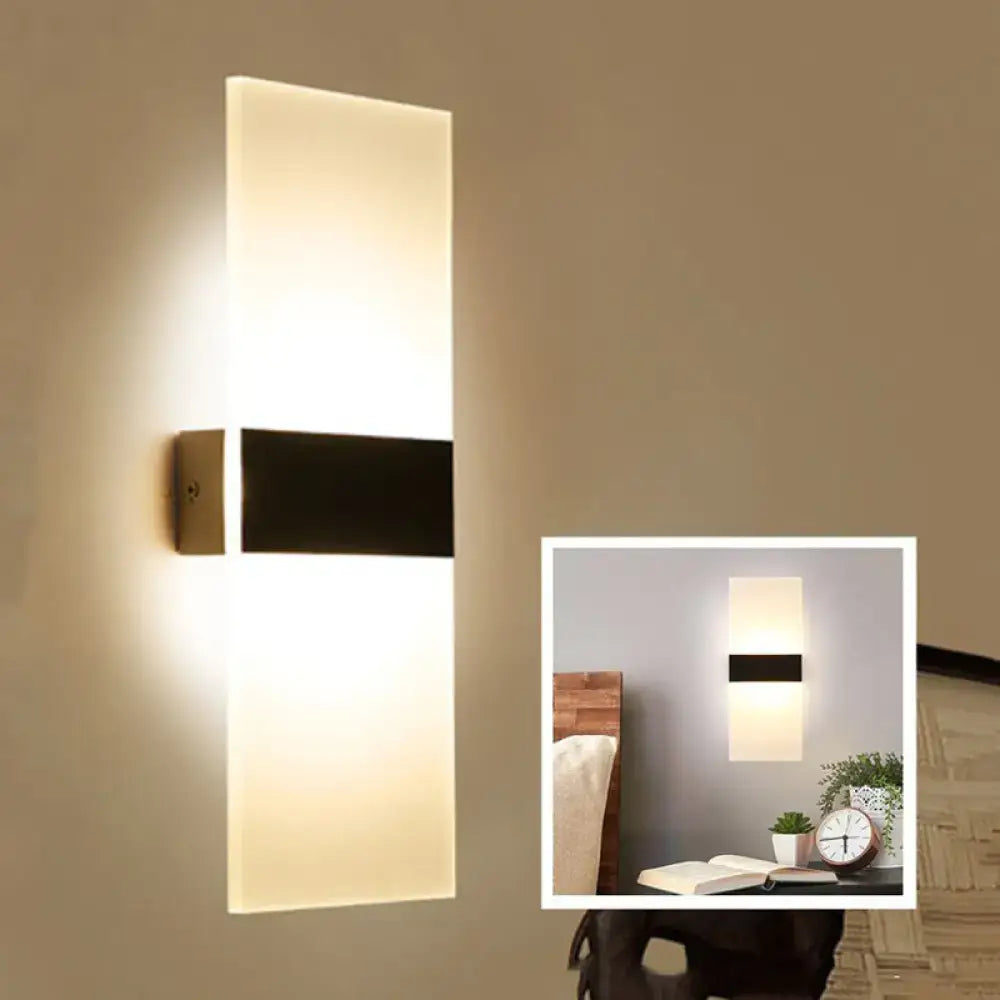 Modern black white rectangular led sconce with frosted glass and black accent bar emitting warm ambient light