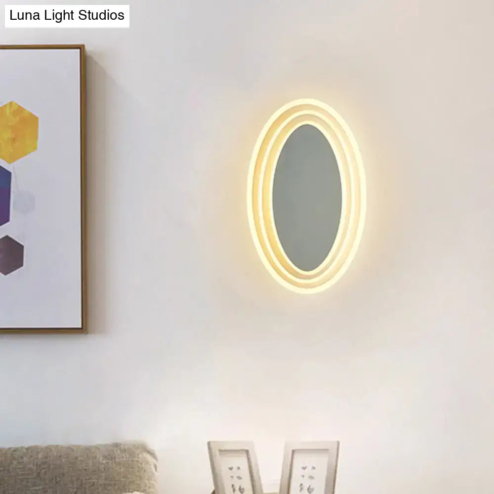 Warm-toned oval black and white rotatable led wall light fixture with glowing led light ring for bedroom wall light mirror