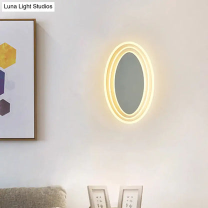 Warm-toned oval black and white rotatable led wall light fixture with glowing led light ring for bedroom wall light mirror