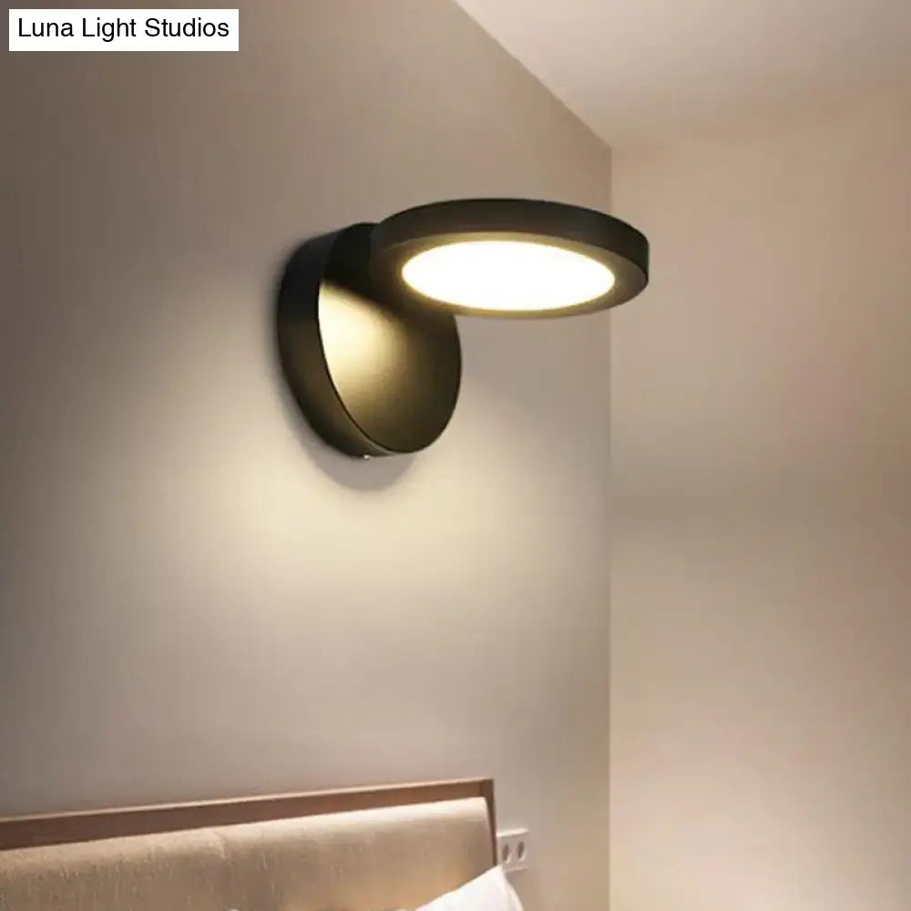 Modern black circular wall light fixture with sleek minimalist design and warm ambient glow for bedroom use